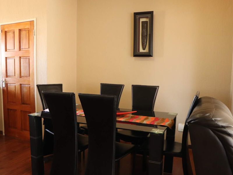 A dining area featuring laminate flooring and a traditional wooden door, providing a functional space for meals.