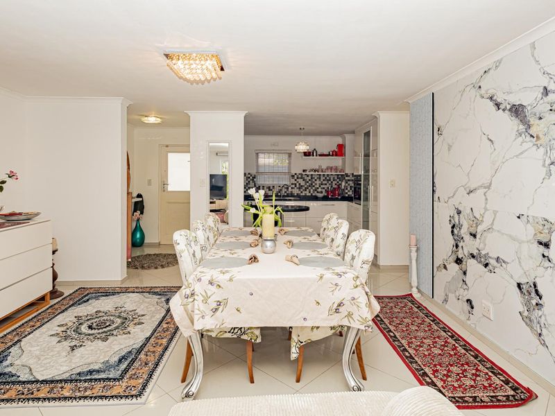 Spacious open-plan living and dining area featuring a striking marble-effect feature wall, tiled flooring, and a seamless transition into the kitchen.