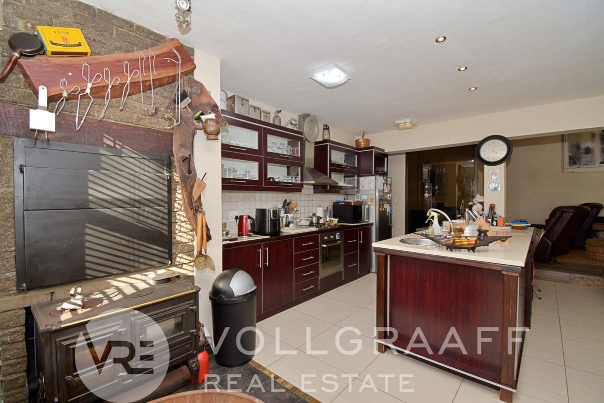 A functional kitchen featuring dark wood cabinetry, a central island with a sink, built-in oven, and an integrated indoor fireplace.
