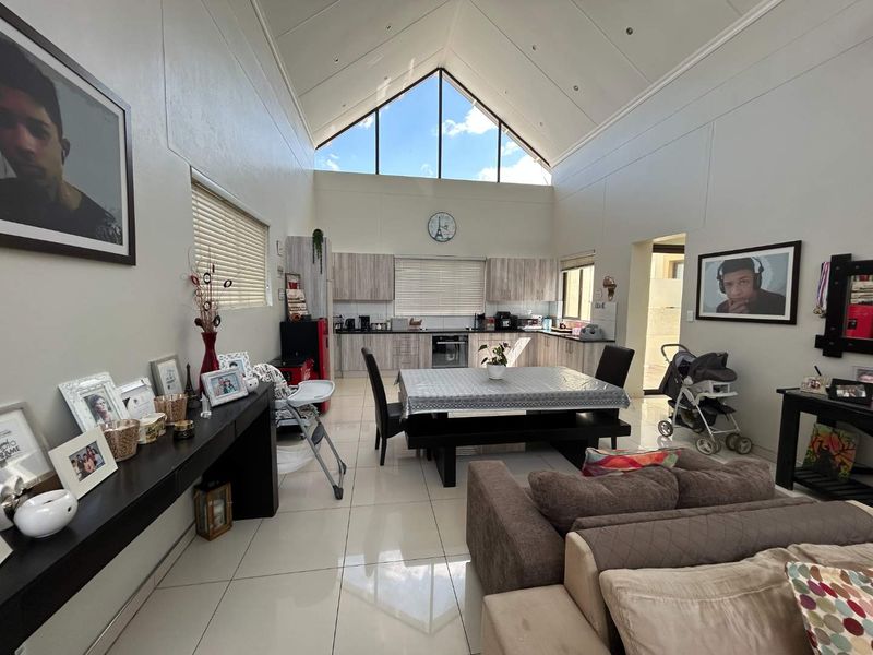 Spacious open-plan living and kitchen area featuring a dramatic vaulted ceiling, large triangular clerestory window, and modern cabinetry with integrated appliances.