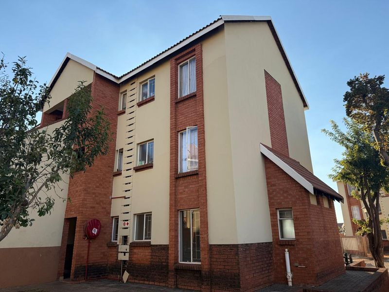 Exterior view of a multi-story apartment building featuring a combination of face brick and plastered walls with a tiled roof.