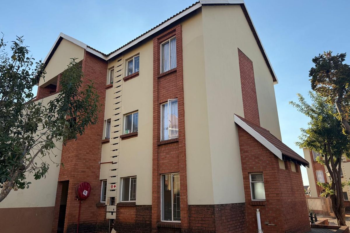 Exterior view of a multi-story apartment building featuring a combination of face brick and plastered walls with a tiled roof.