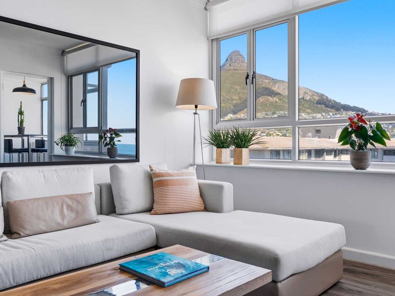 Bright living room featuring large windows with mountain views, neutral walls, and modern laminate flooring.