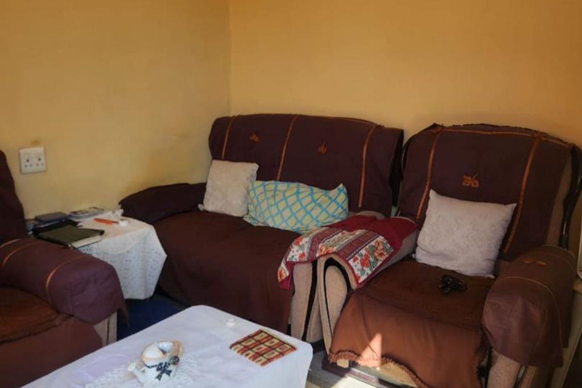 A living room space featuring laminate flooring and yellow painted walls, providing a functional area for relaxation.