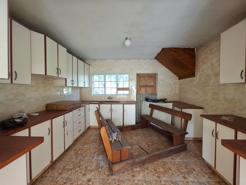 A dated kitchen featuring laminate cabinetry, tiled surfaces, and a double sink, offering a blank canvas for a modern renovation.