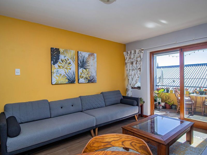 A living room featuring tiled flooring and a large sliding glass door providing access to an outdoor balcony area.