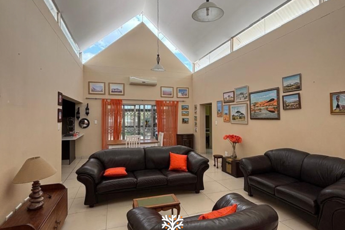 Spacious living room featuring a high vaulted ceiling with clerestory windows, tiled flooring, and a wall-mounted split-system air conditioner.