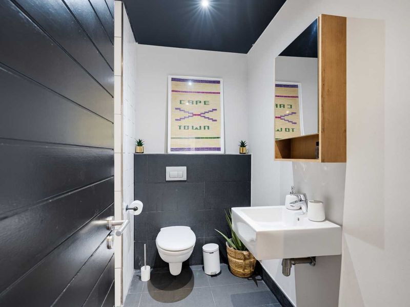 Modern guest bathroom featuring a wall-hung basin, wall-mounted toilet with concealed cistern, and a sleek mirrored medicine cabinet.
