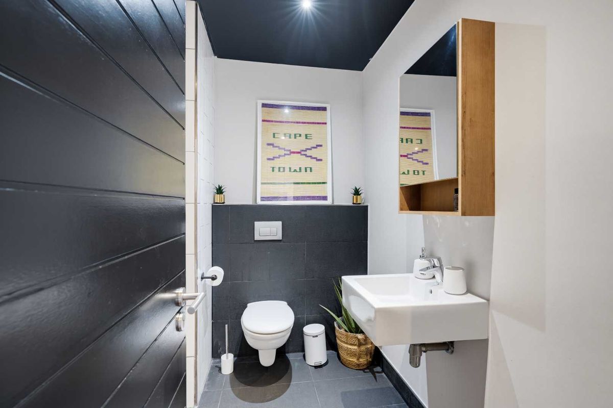 Modern guest bathroom featuring a wall-hung basin, wall-mounted toilet with concealed cistern, and a sleek mirrored medicine cabinet.