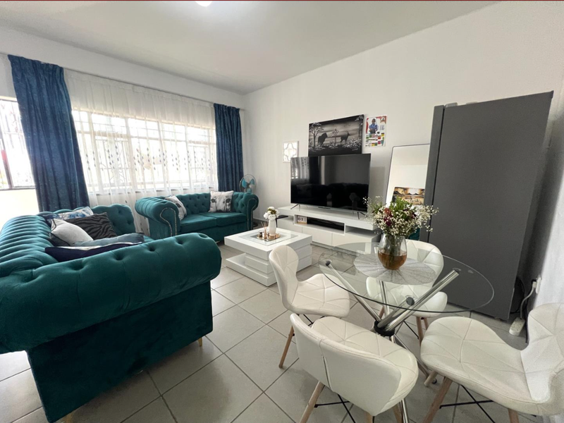 An open-plan living and dining area featuring neutral tiled flooring and a large window that provides ample natural light.
