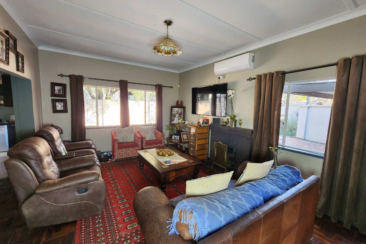 A comfortable living room featuring a brick fireplace, split-system air conditioning, and classic parquet flooring, offering a warm and inviting atmosphere.