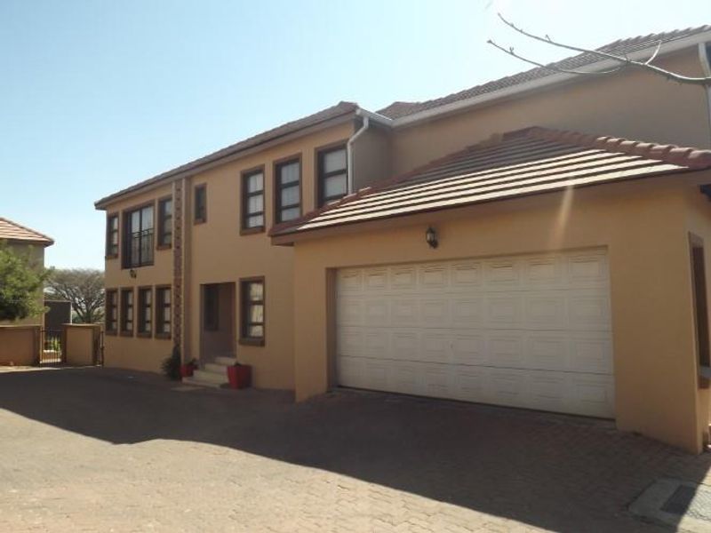 Front elevation of a double-storey townhouse featuring a paved driveway, integrated double garage, and neutral exterior finish.
