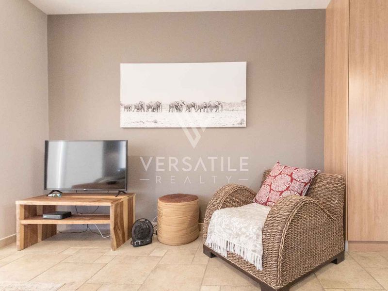 A living area featuring neutral wall tones, tiled flooring, and a built-in wardrobe providing functional storage space.