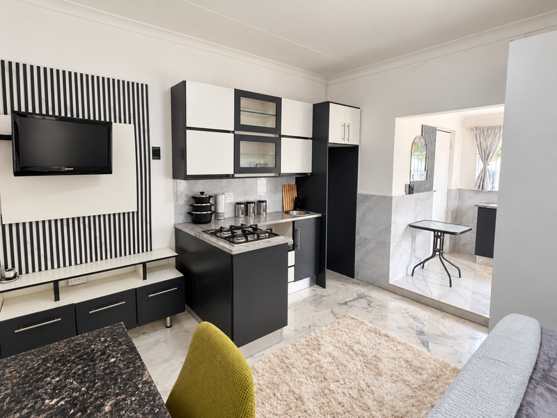 Modern open-plan kitchen and living area featuring sleek two-tone cabinetry, gas hob, and elegant marble-look tiling throughout.