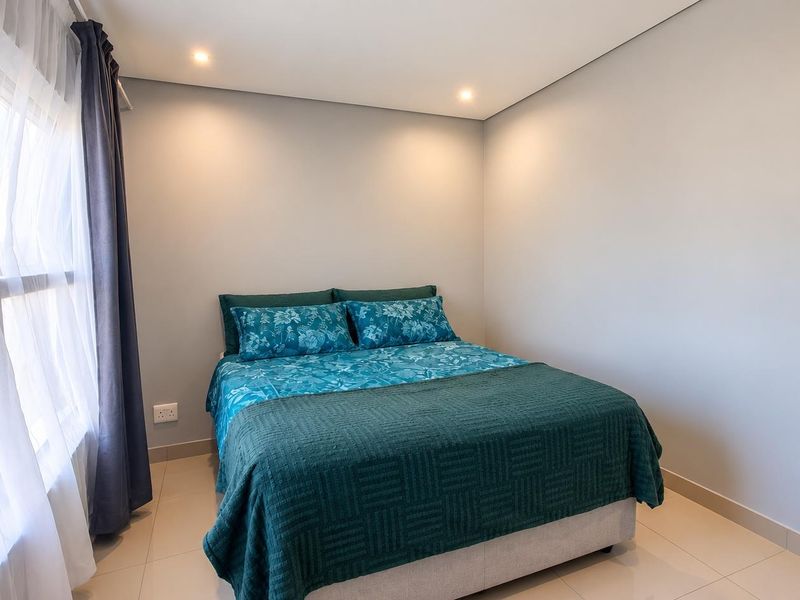 A well-maintained bedroom featuring neutral wall tones, recessed downlighting, and tiled flooring, providing a clean and functional living space.