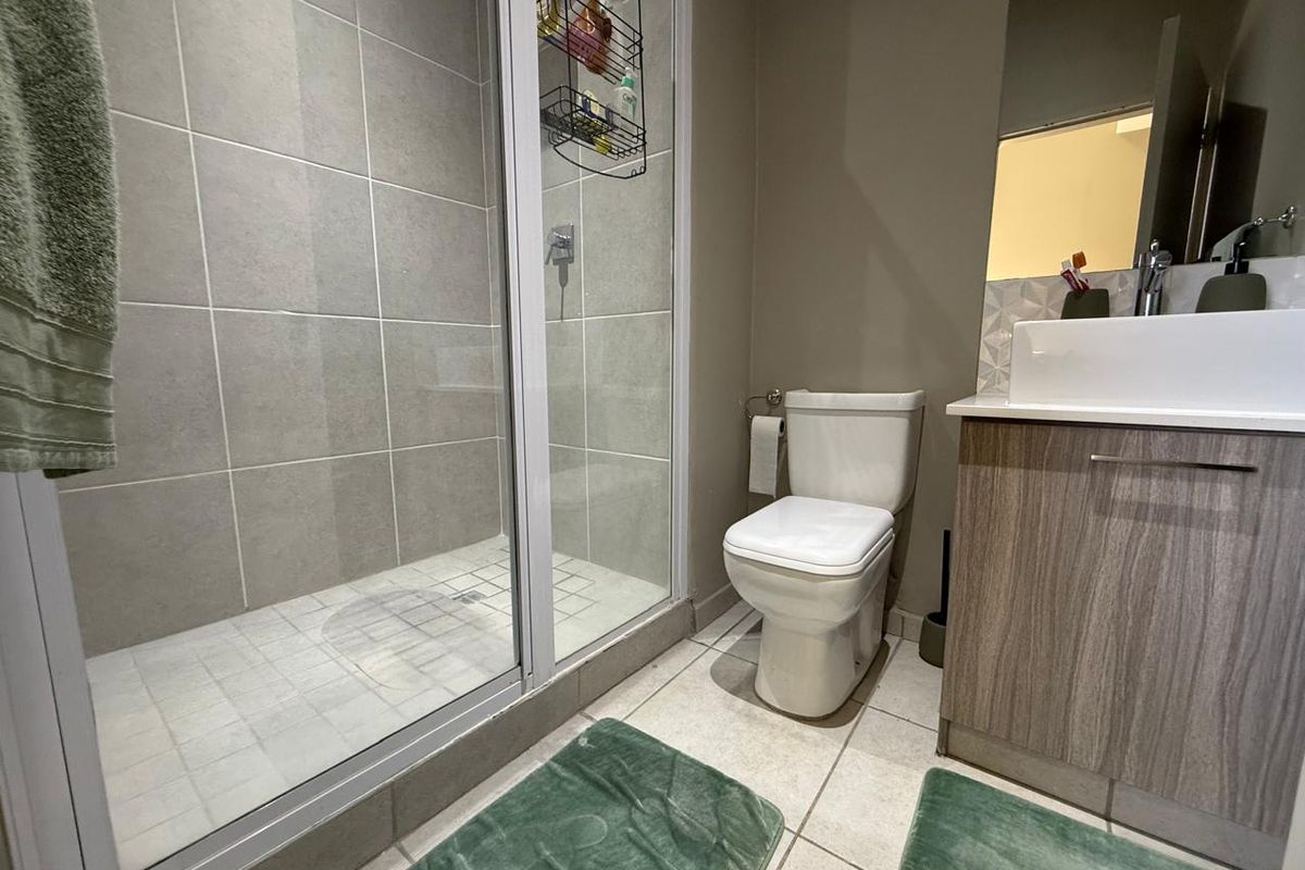 Modern bathroom featuring a glass-enclosed shower, a contemporary vessel sink with a vanity cabinet, and neutral wall tones.