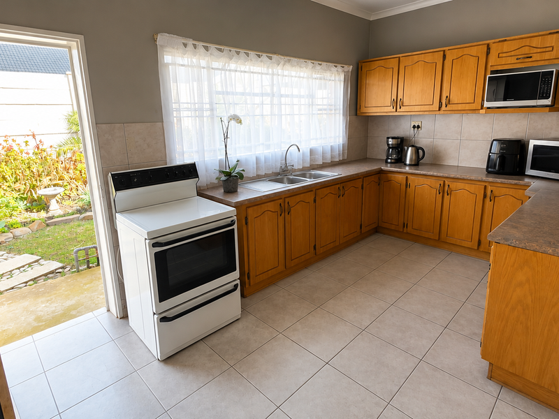 A functional kitchen featuring wooden cabinetry, laminate countertops, a double basin sink, and direct access to the rear garden area.