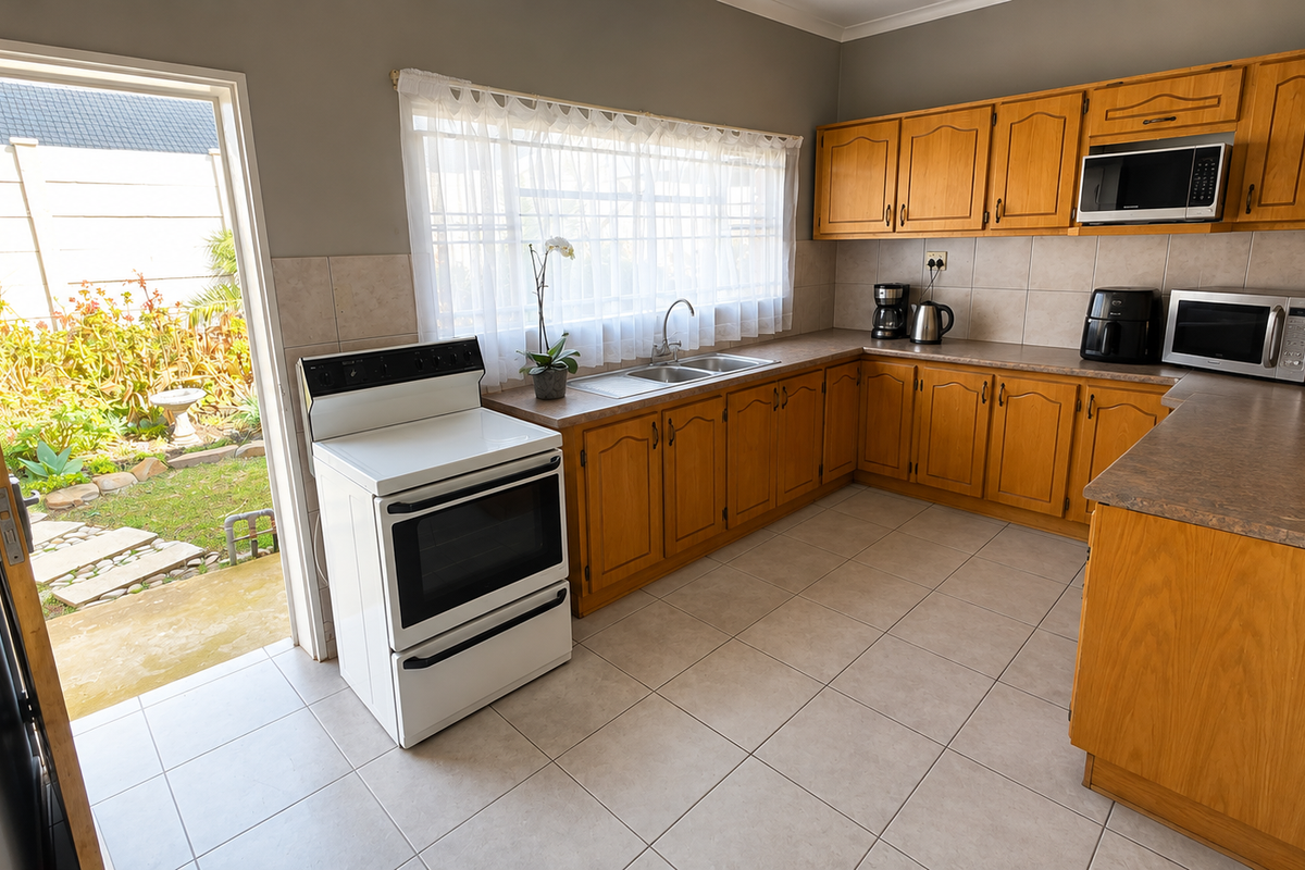 A functional kitchen featuring wooden cabinetry, laminate countertops, a double basin sink, and direct access to the rear garden area.