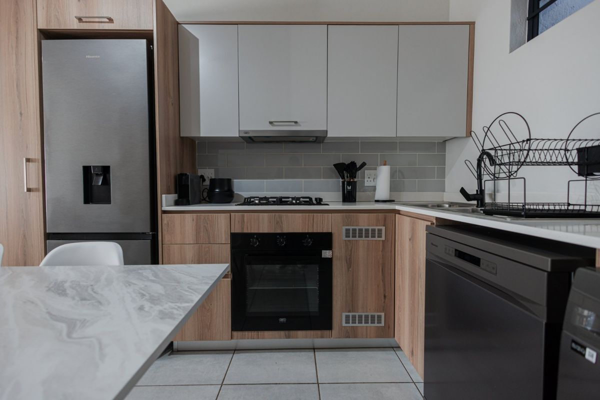 Modern kitchen featuring wood-grain cabinetry, stone countertops, subway tile backsplash, and integrated appliances including a gas hob and oven.