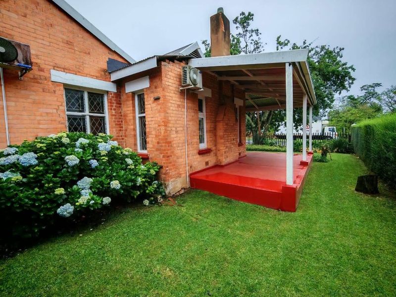 Rear view of the office building featuring a covered patio, brick exterior, and established garden area.