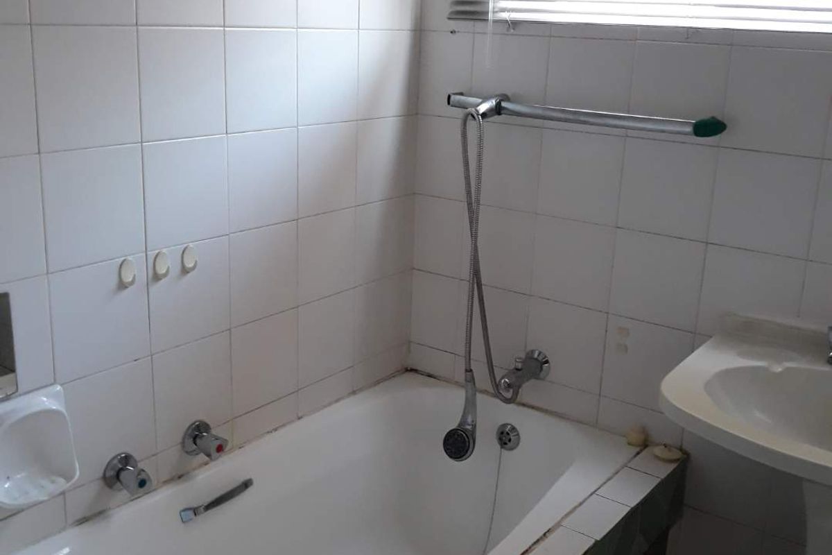 A dated bathroom featuring a standard bathtub, pedestal basin, and wall tiling. The space requires cosmetic updates to improve its overall condition and appeal.