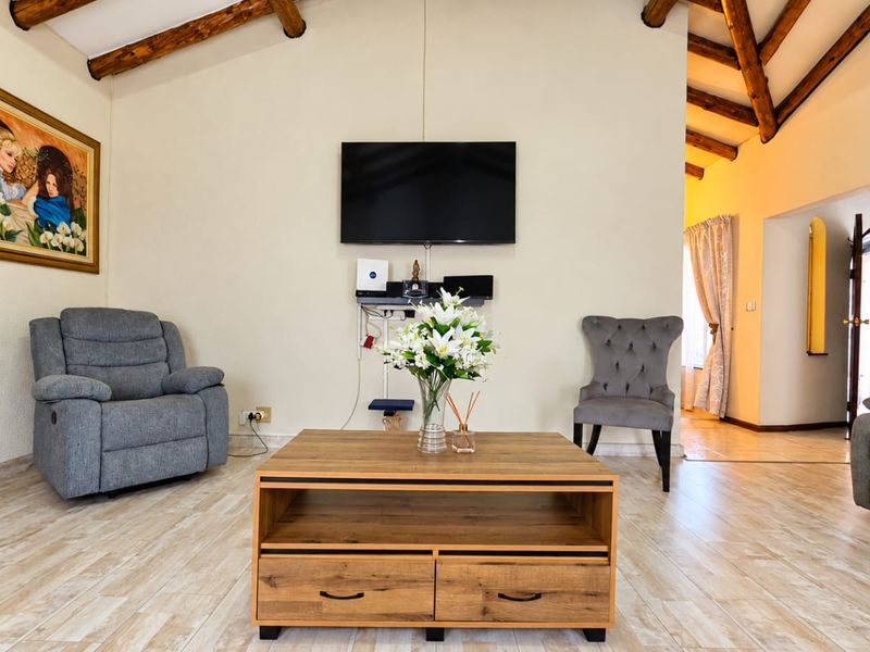 A comfortable living room featuring exposed timber ceiling beams and light-toned tiled flooring, creating a warm and inviting atmosphere.