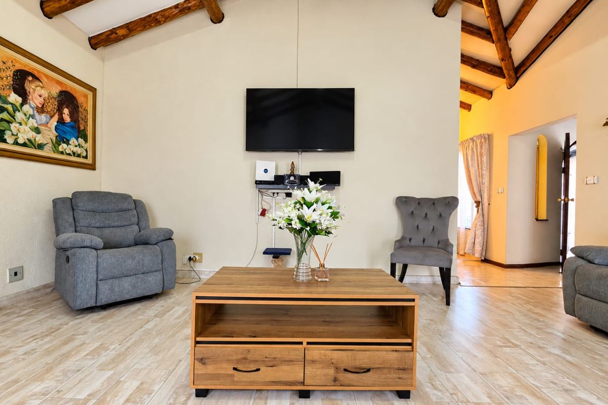 A comfortable living room featuring exposed timber ceiling beams and light-toned tiled flooring, creating a warm and inviting atmosphere.