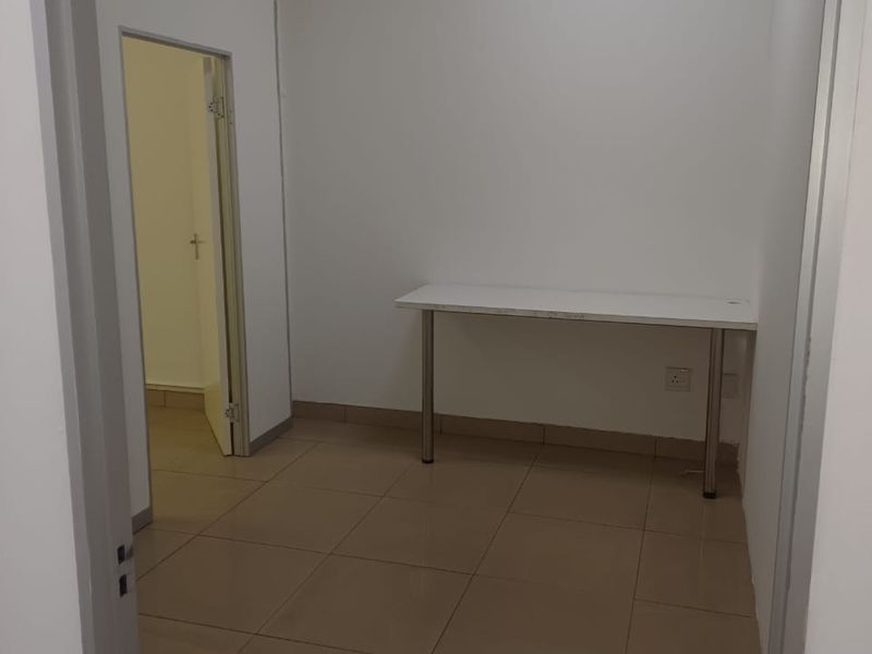 A simple, empty office space featuring neutral tiled flooring and white walls, suitable for a professional workspace.