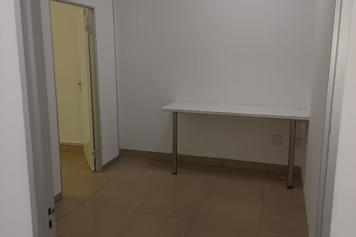 A simple, empty office space featuring neutral tiled flooring and white walls, suitable for a professional workspace.