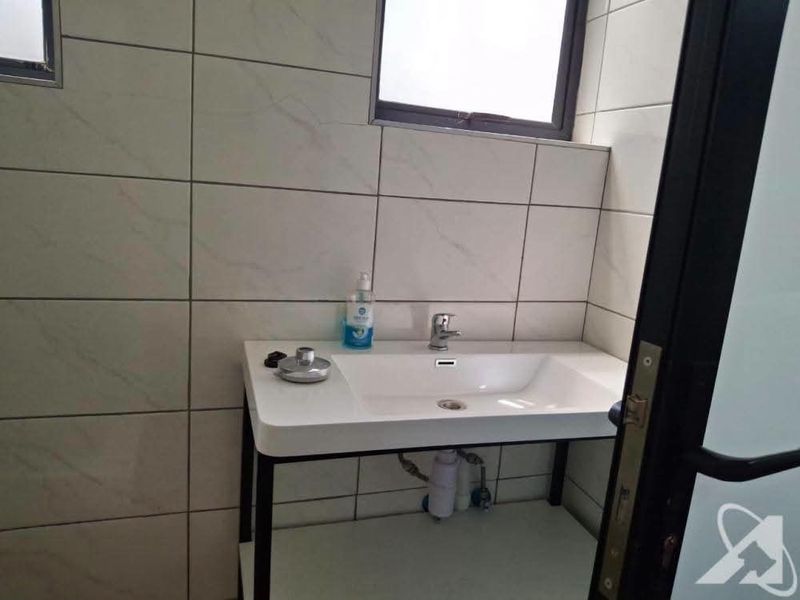 A clean, modern bathroom featuring a wall-mounted basin with a chrome mixer tap and neutral tiled walls.