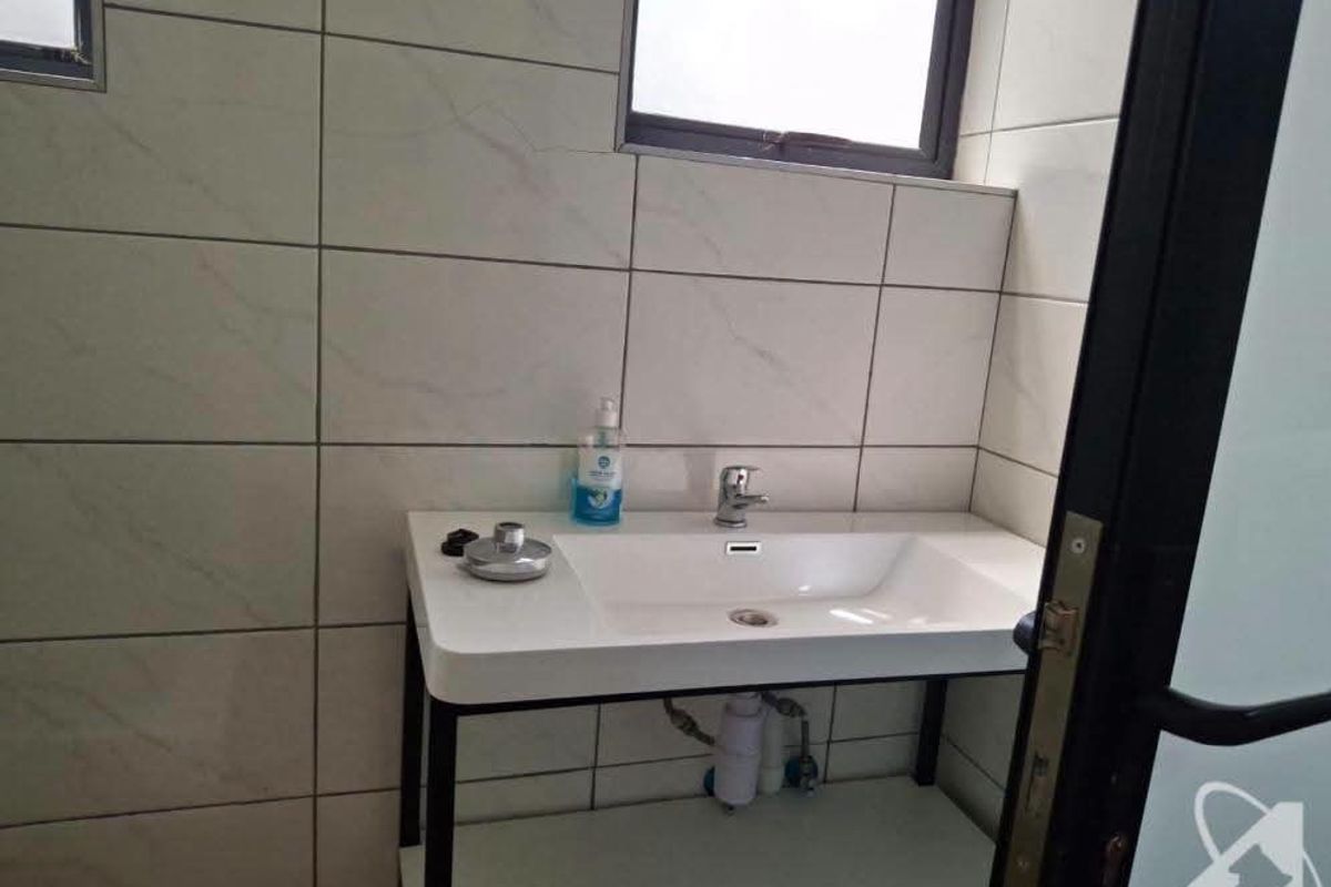 A clean, modern bathroom featuring a wall-mounted basin with a chrome mixer tap and neutral tiled walls.