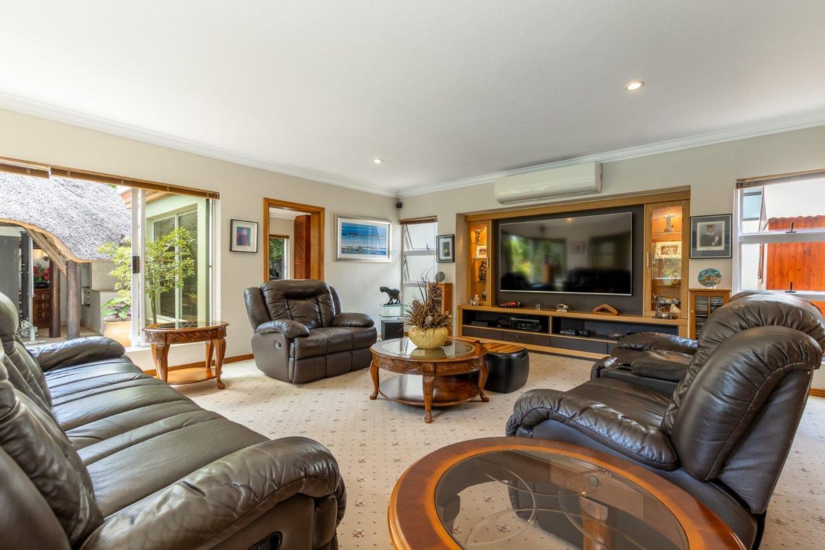 Spacious living room featuring a built-in media wall unit, recessed downlighting, and a wall-mounted air conditioning unit with sliding door access to the patio.