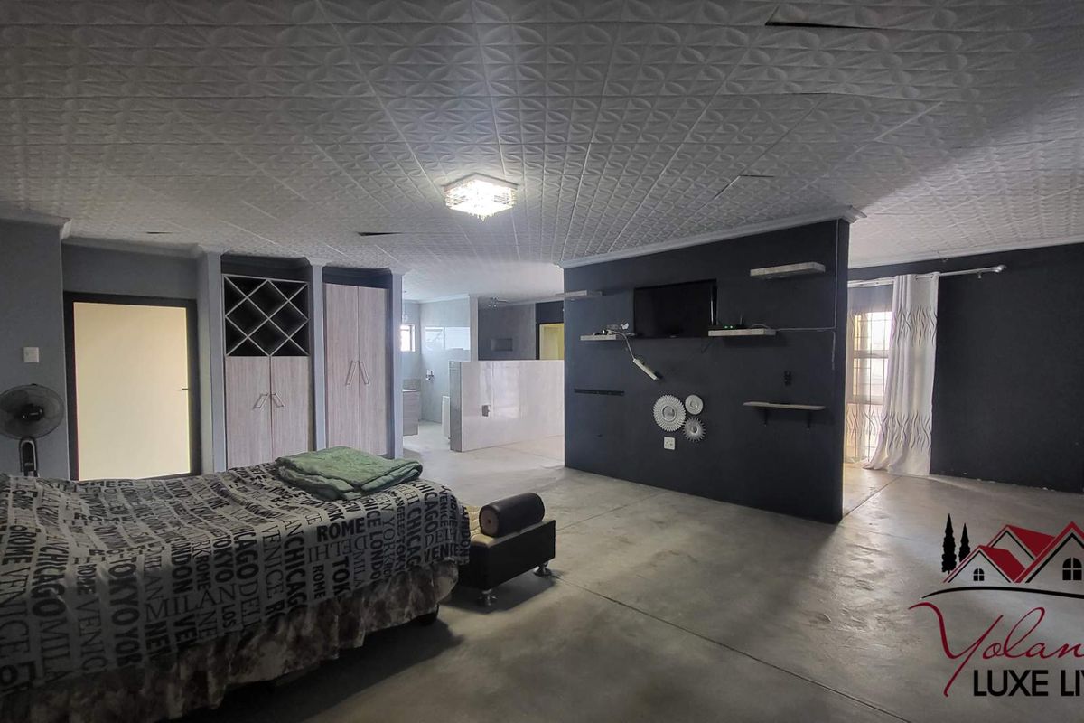 Spacious bedroom featuring a partition wall, built-in cupboards with integrated wine storage, and a textured ceiling.