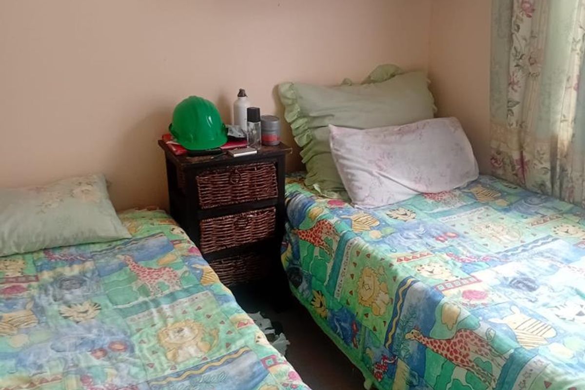 A bedroom featuring built-in wall shelving and window curtains.