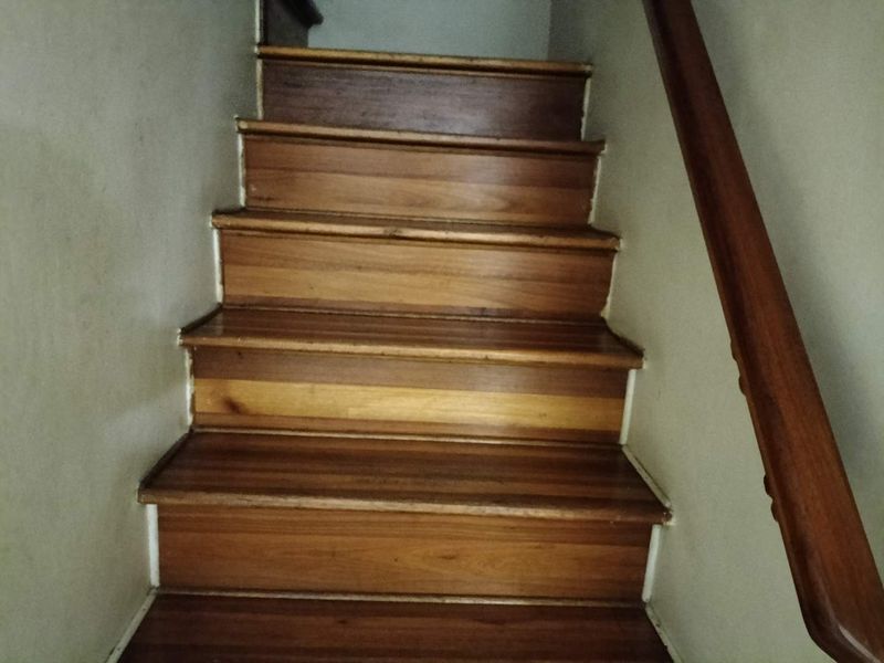 A staircase featuring wooden treads and a matching wooden handrail, showing signs of normal wear and tear.