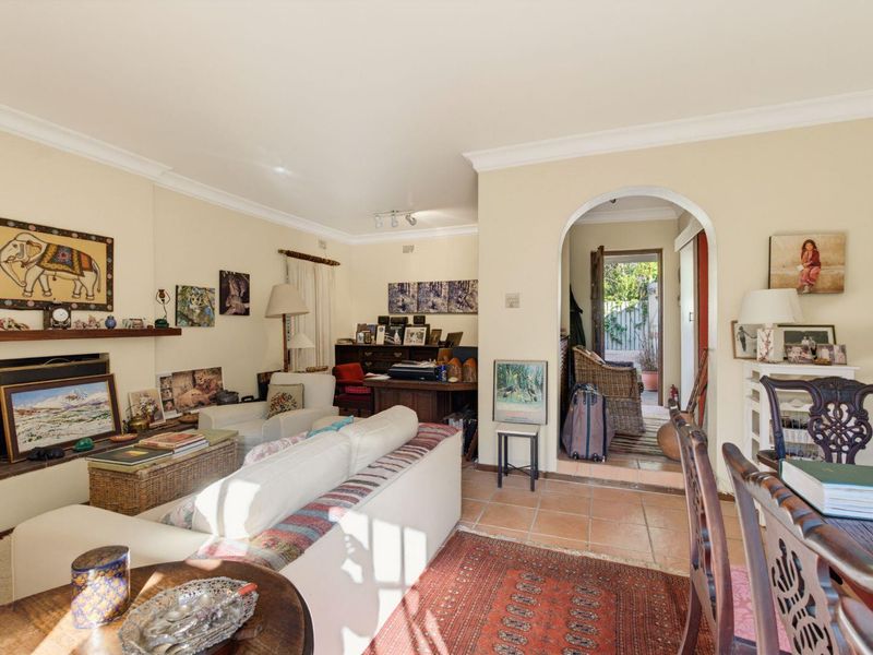 Open plan living and dining area featuring a fireplace, terracotta floor tiles, and an arched doorway leading to an outdoor patio space.