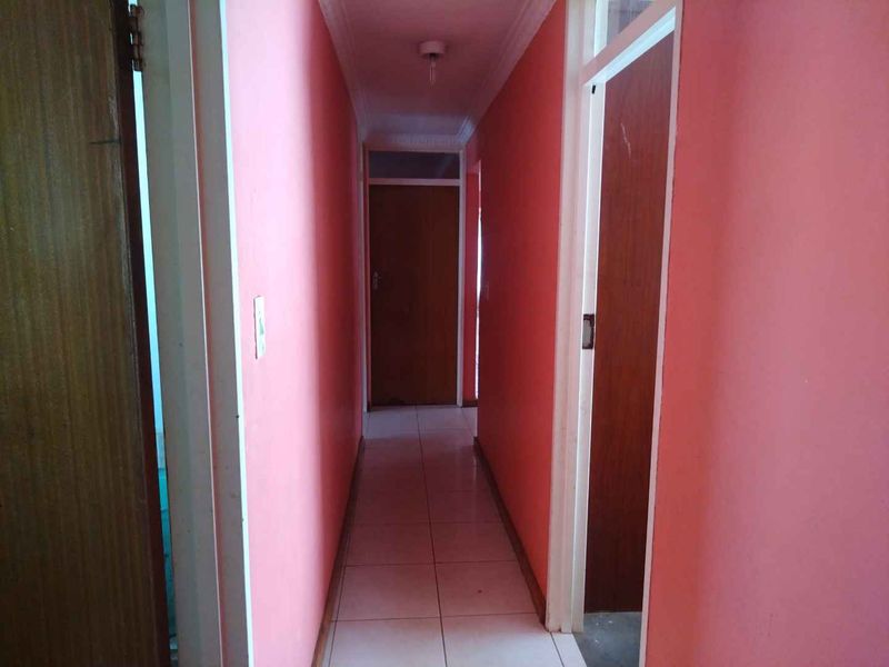 A narrow residential hallway featuring tiled flooring and coved ceiling cornices, providing access to multiple rooms.