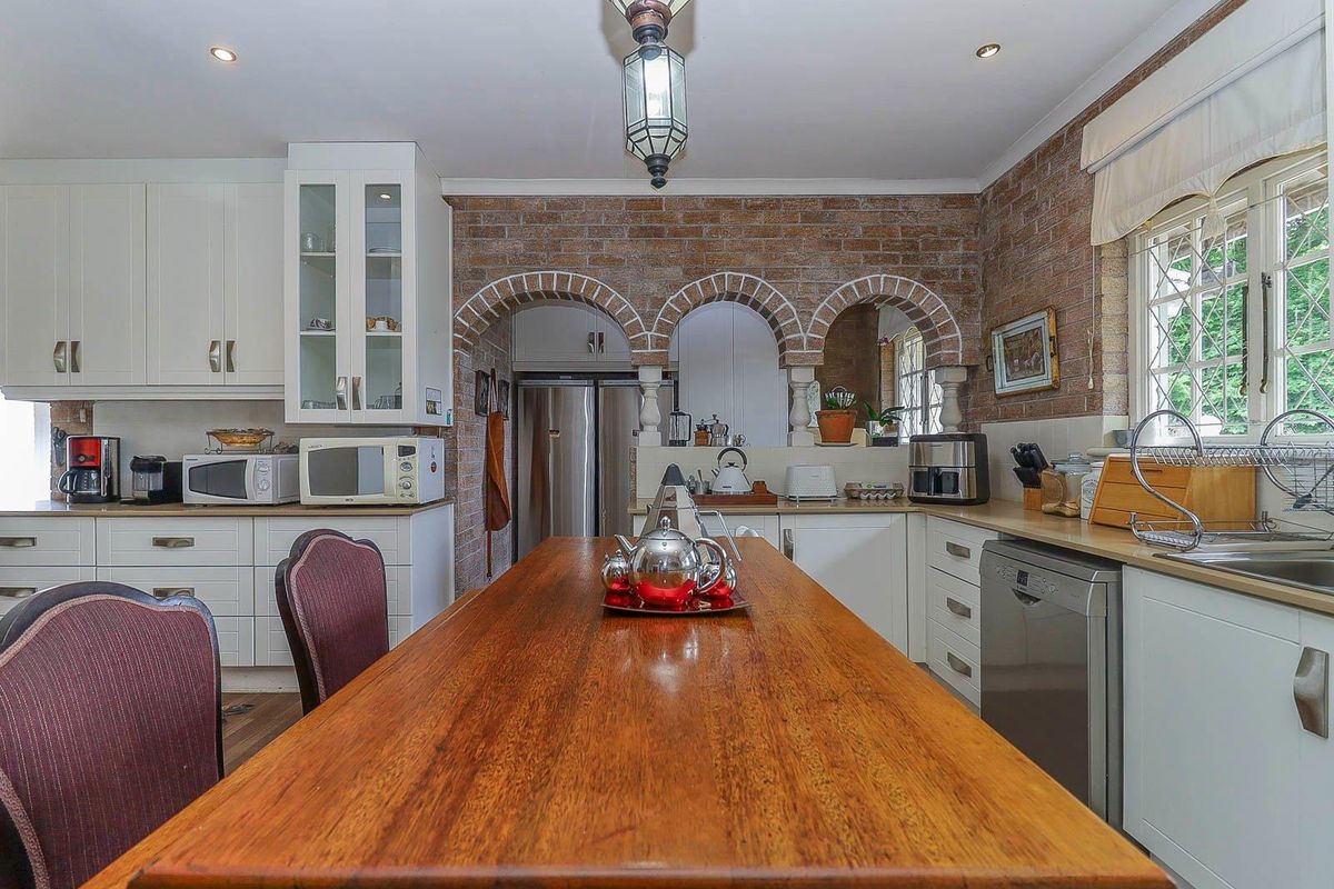 A traditional kitchen featuring white cabinetry, exposed brick archways, a central wooden island, and integrated appliances, offering a classic and functional culinary space.