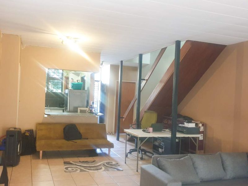 Open-plan living area featuring a staircase, tiled flooring, and a kitchen pass-through, offering a versatile layout for dining and relaxation.