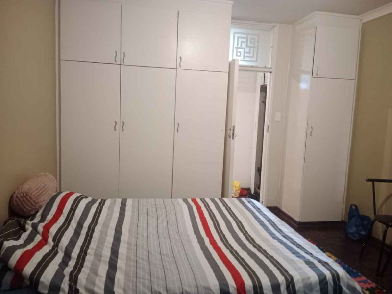 Bedroom featuring extensive built-in floor-to-ceiling cupboards and traditional parquet flooring, offering ample storage space within the apartment.