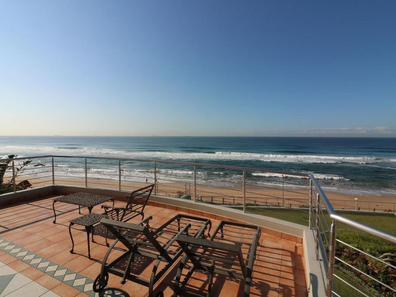 Spacious balcony featuring tiled flooring and a stainless steel balustrade, offering panoramic ocean and beach views.
