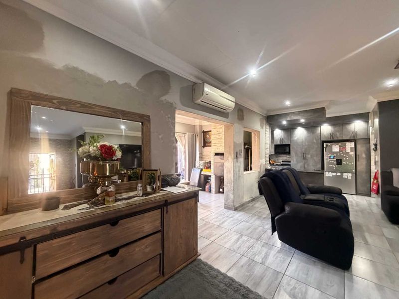 Open-plan living and kitchen area featuring tiled floors, recessed lighting, and split-system air conditioning, currently requiring wall finishing and cosmetic updates.