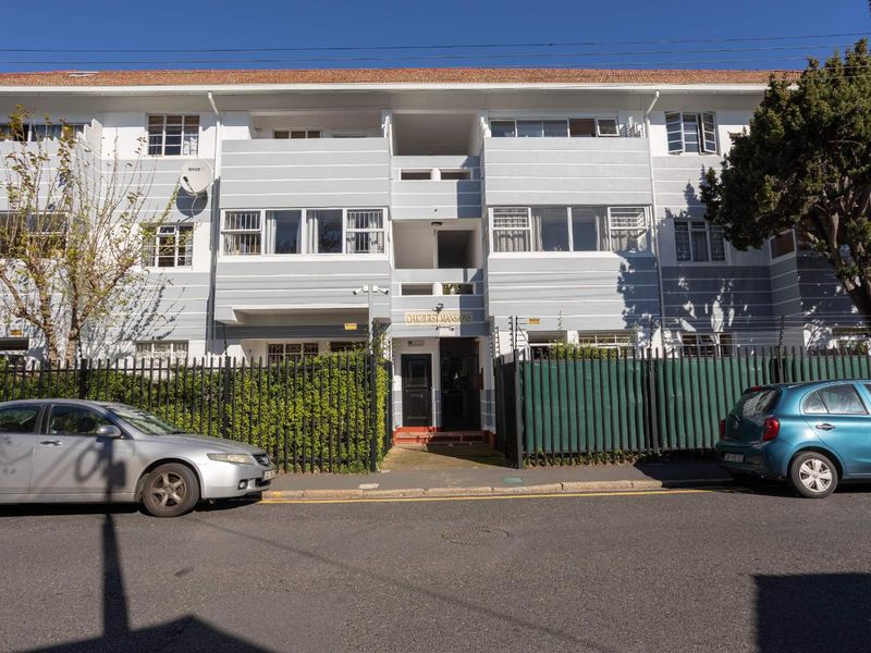 Front elevation of Oakhurst Mansions apartment building featuring a tiled roof, secure gated entrance, and perimeter electric fencing.