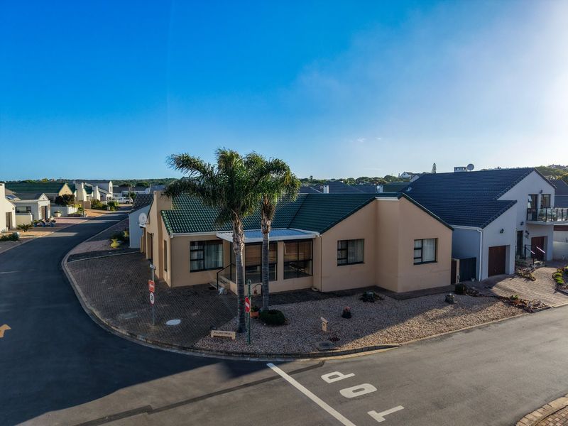 A corner-lot residential property featuring a tiled roof, paved driveway, and a covered entrance area in a quiet suburban street setting.