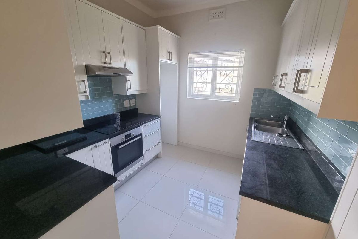 A clean, modern kitchen featuring white cabinetry, dark granite countertops, a subway tile backsplash, and integrated stainless steel appliances.