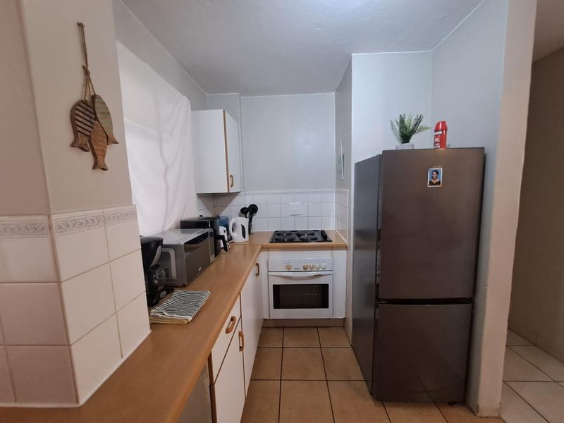 A compact kitchen featuring built-in cabinetry, a tiled splashback, laminate countertops, and a built-in oven with an electric hob.