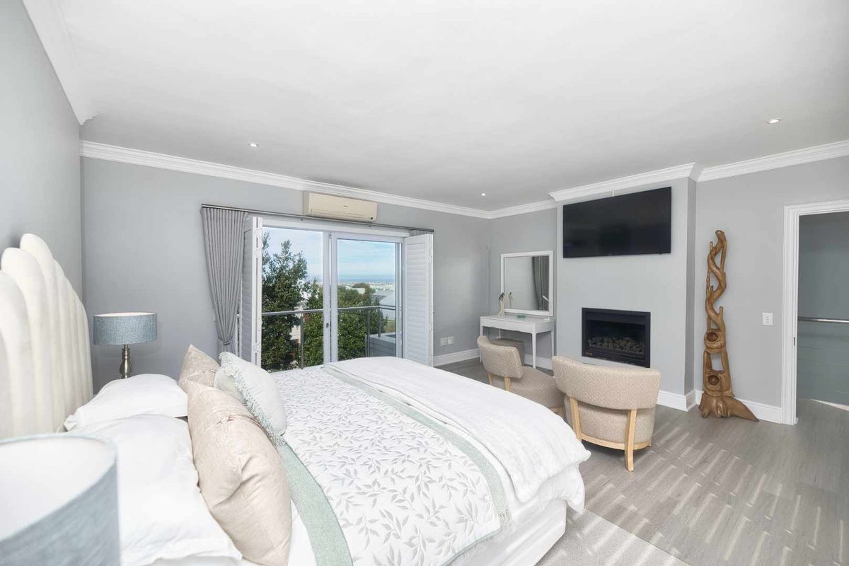 Spacious bedroom featuring a built-in fireplace, split-system air conditioning, and sliding glass doors opening to a balcony with scenic views.