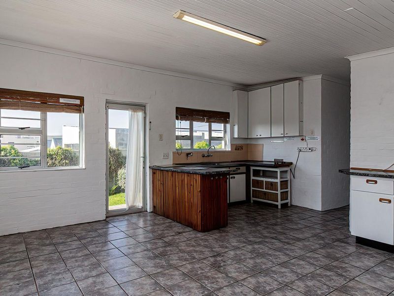 A functional kitchen space featuring tiled flooring, built-in cabinetry, and direct access to the exterior, offering a blank canvas for modern renovation.