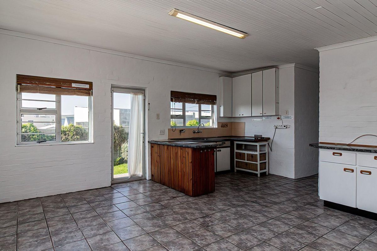A functional kitchen space featuring tiled flooring, built-in cabinetry, and direct access to the exterior, offering a blank canvas for modern renovation.
