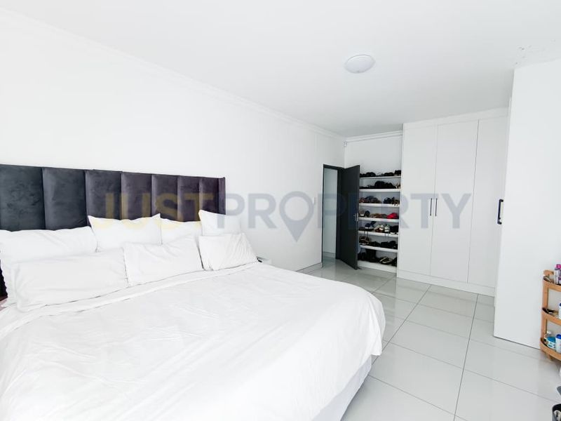 Spacious bedroom featuring neutral tiled flooring, ample built-in cupboard storage, and a clean, minimalist aesthetic.